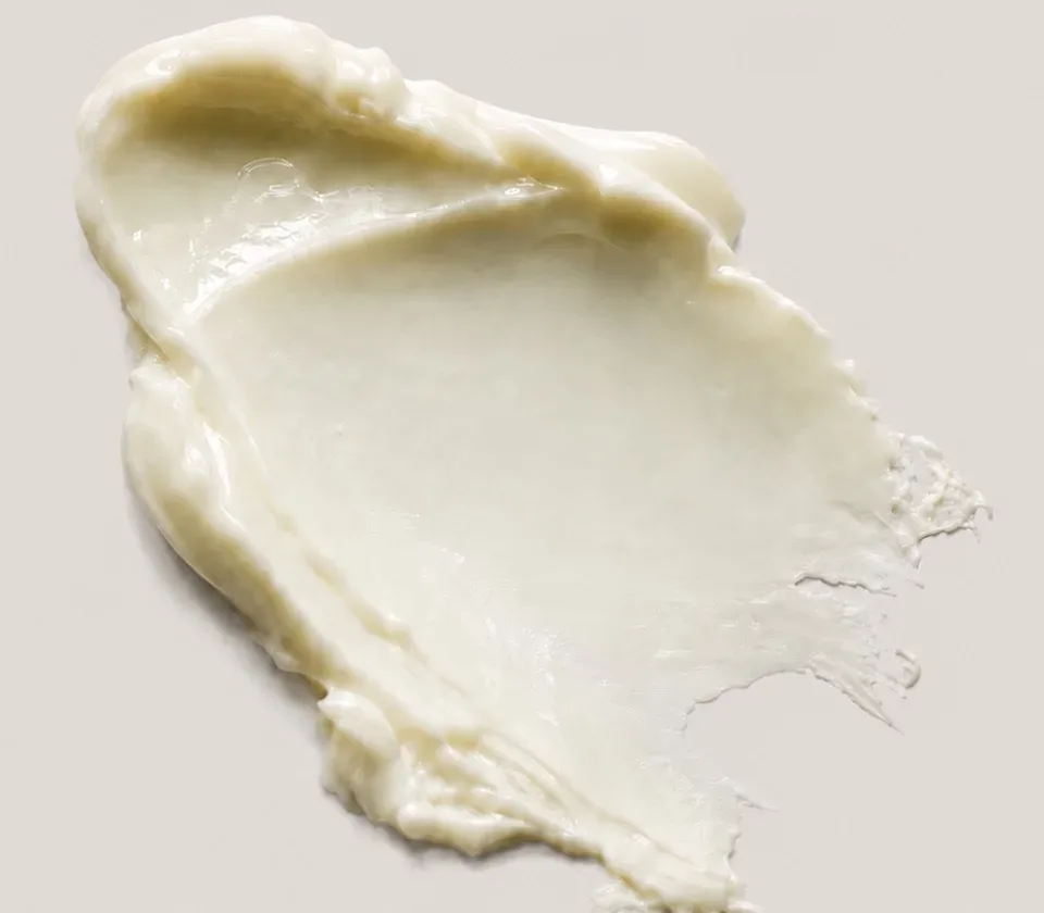 Nærbillede af en strøg lys, tæt creme på en grå flade.
