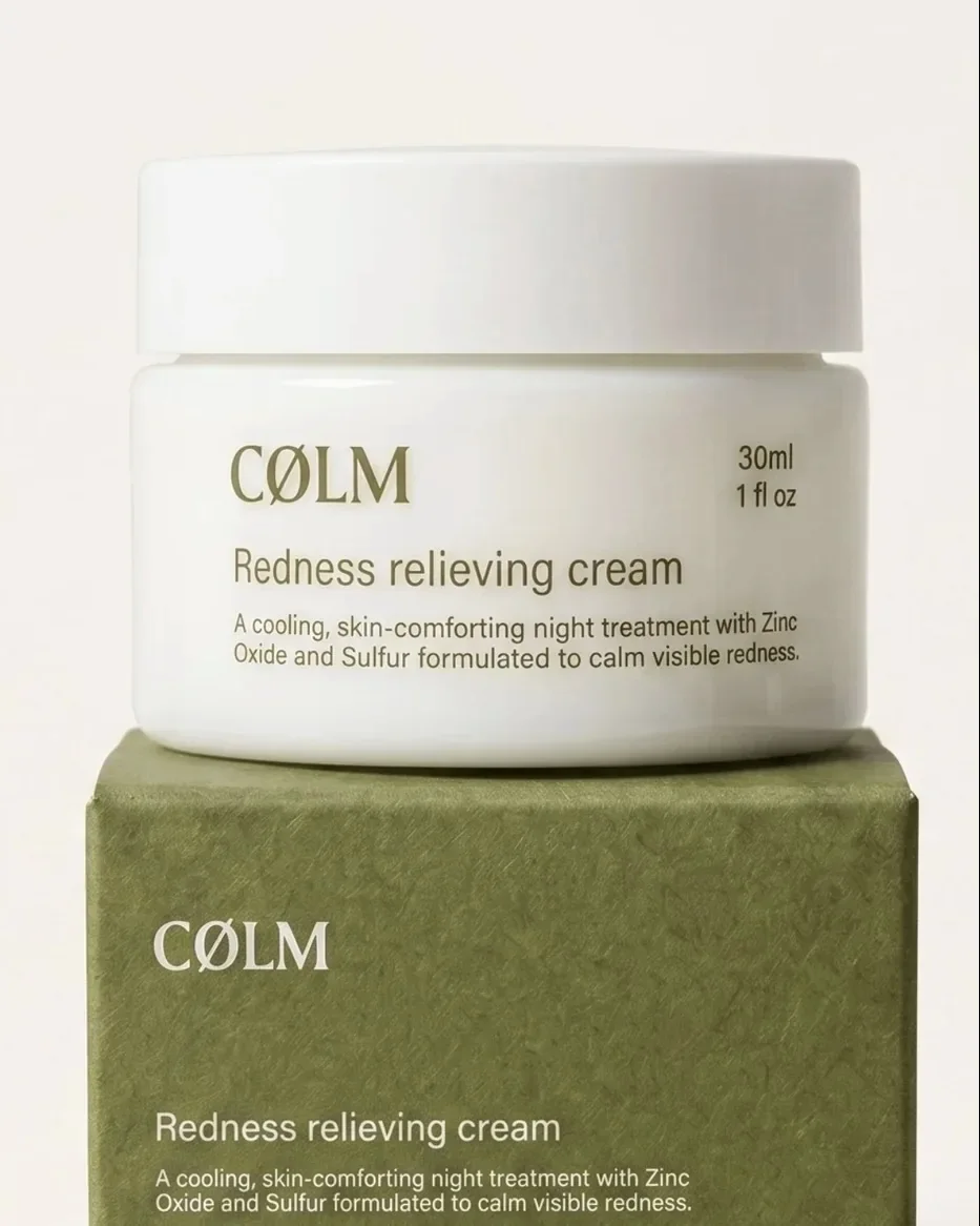 En hvid krukke med CØLM Redness Relieving Cream stillet oven på dens olivengrønne æske.